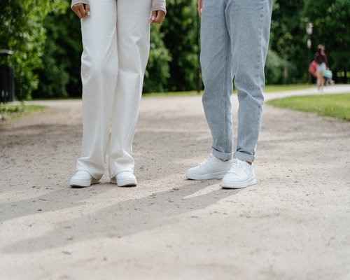 A person wearing comfortable shoes while walking leisurely along a city path surrounded by trees